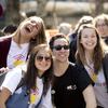 A diverse group of happy young adults laughing and smiling in white T-shirts, at a public event.